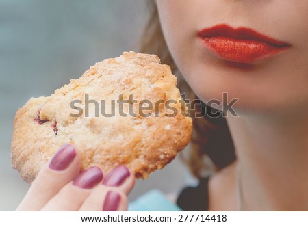 Young woman holding big cookie powdered sugar copy space