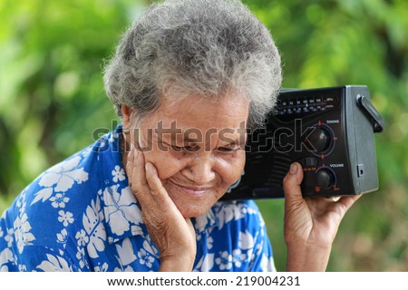 Old Woman Listening To Music With A Vintage Radio, outdoor