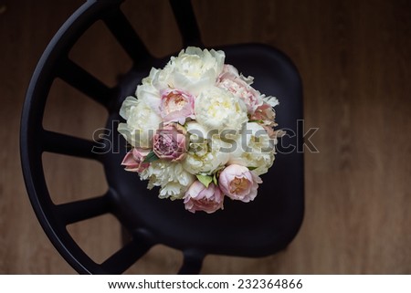 Bouquet of white flowers tied with a pink ribbon on a black chair