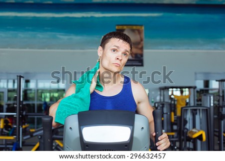 Man at the gym exercising on the xtrainer machine with towel after training
