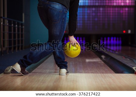 Male legs and bowling ball in alley.