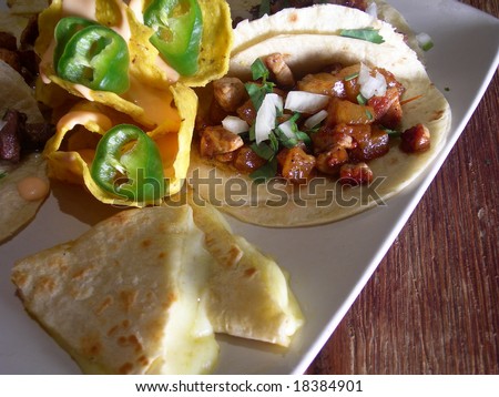 Meat mexican tacos with hot sauce, nachos, quesadillas, jalapenos and cheese sauce, in a mexican restaurant.