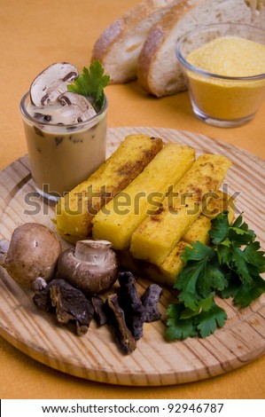 Grilled polenta fingers with mushrooms and mushroom sauce on a wood table