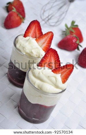 Vase of strawberries with cream and marmalade, on a white mat