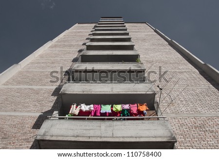 A block of flats, empty but one flat, with colorful laundry drying