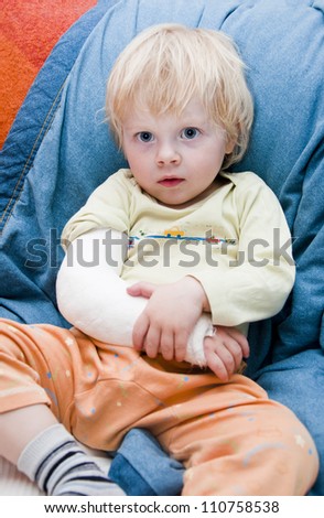 Little boy with a broken arm sitting on a couch