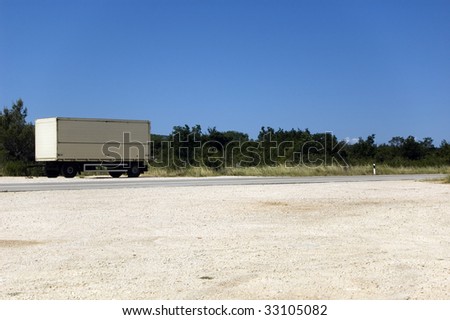 Forlorn trailer by the road with empty gravel parking space in the front and clear blue sky in the background