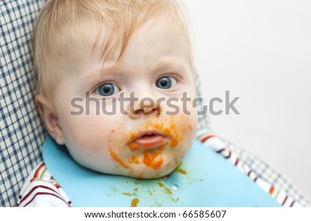 Little kid dirty with food on the face looking straight into the camera