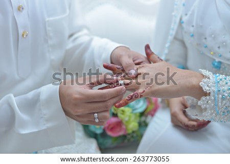 malay wedding groom bolstering gold ring on bride\'s finger