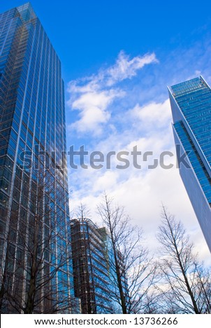 Skyscraper against a blue sky reflecting trees in Canary Wharf, London