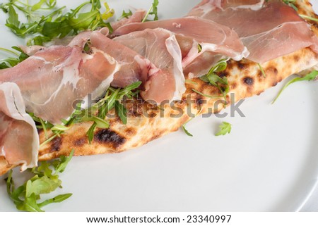 Calzone con spek e rucola. Italian pizza with smoked ham. Focus on ham.