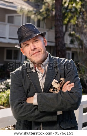 Cool man with hat smiling at the camera with crossed arms