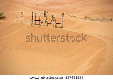 6 black chairs on the top of sand dunes at Sahara desert