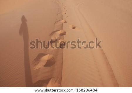 left shadow and foot step on sand dune, Sahara desert, Morocco