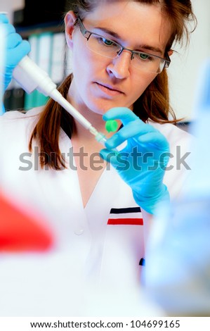 Portrait of a scientist with an automatic pipette in modern laboratory, shallow DOF