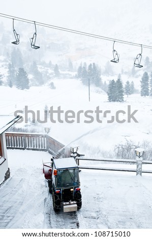 Tractor cleans snow from wooden platform by the ski lift in resort Oberthauern in Austrian Alps