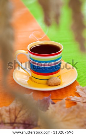 Autumn cup of black coffee on orange and green table cloth