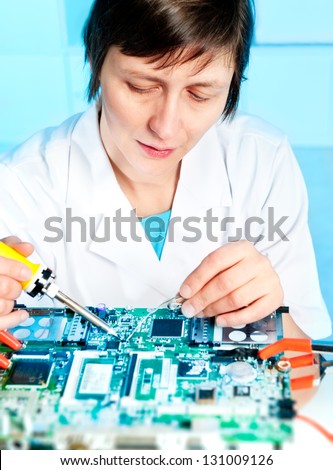 Electronics repair tech is soldering a circuit board
