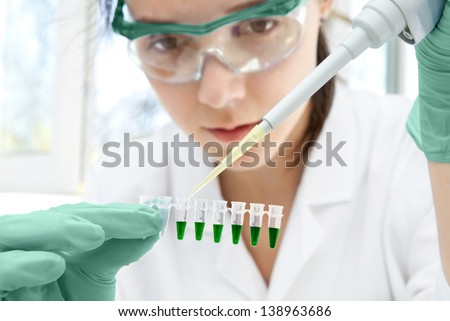 Young female scientist loads samples for DNA amplification by PCR into plastic tubes Young female scientist loads samples for DNA amplification by PCR into plastic tubes