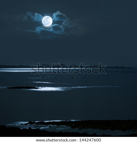 Full Moon over calm sea with a distanc shore