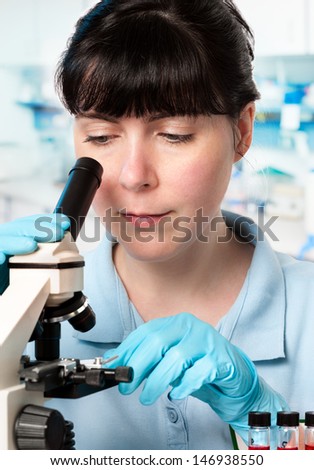 Young trainee or graduate student works with microscope in laboratory
