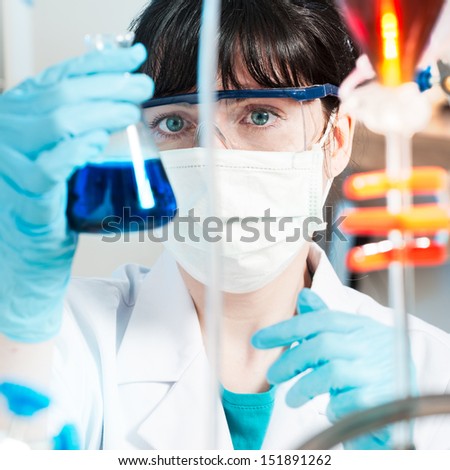 Young chemist in protective wear observes reaction in conical flask