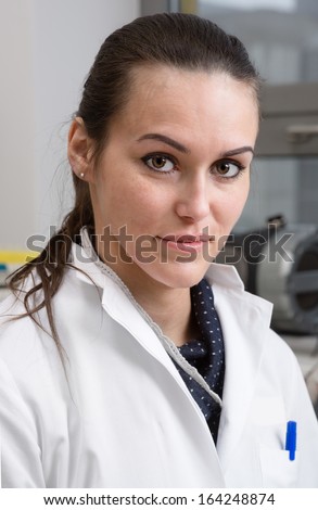 Young scientist, tech or PhD student in white coat looks at the camera