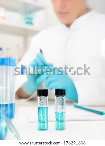 Scientific samples in research laboratory with a scientist in background, shallow DOF