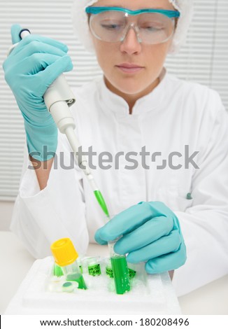 Young female tech or scientist works with automatic pipette