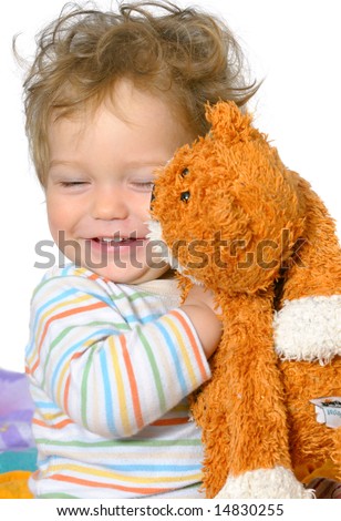 stock photo : one year old boy with curly hair is hugging his ginger cat;