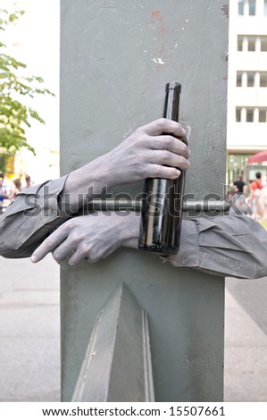 hands painted grey with wine bottle wrapped around a column; man drinking; conceptual shot
