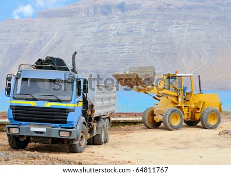 front end loader loading a truck on a shore of Graciosa; Canary islands, Spain