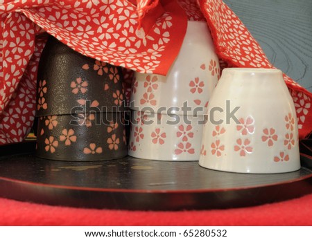 Japanese porcelane cups under red cotton cloth with matching floral design. The shot was made in one of the small stalls offering tea by Kiomizu Dera temple in Kyoto, famous for its tasty water.