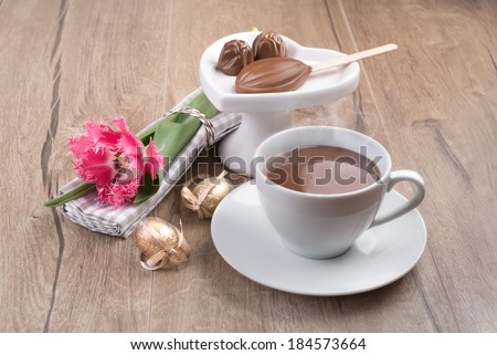 Hot chocolate, pralines and stick of soluble chocolate on wooden table