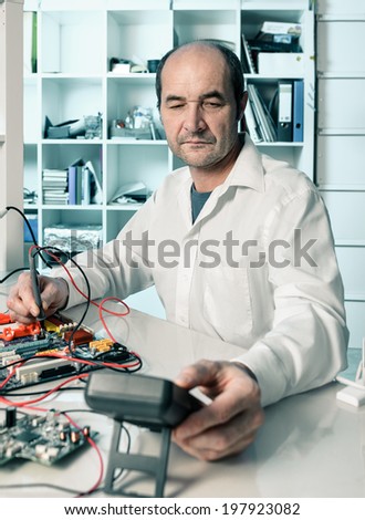 Senior male tech tests electronic equipment