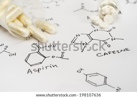 Aspirin in capsules and caffeine in tablets on paper with their chemical formula