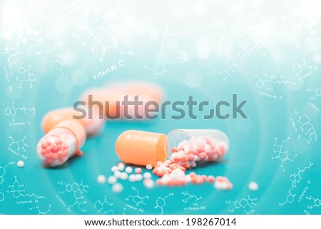 Closeup on vitamin capsule on blue-green background in a frame of chemical formula of various vitamins