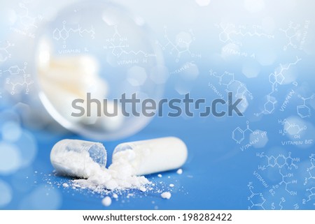 Closeup on vitamin capsule on blue background in a frame of chemical formula of various vitamins