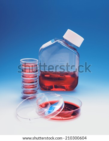 Bacterial plates and a flask of culture medium on blue gradient background