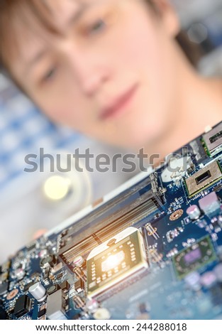 Closeup on motherboard observed by a tech for possible defects