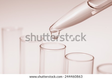 Scientific background: drop from pipette falling in a tube, sepia toning, text space