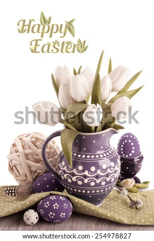 Easter greeting card with white tulips in purple ceramic jug and matching Easter eggs. Top of the picture is isolated on white with space for your text. This image is toned.