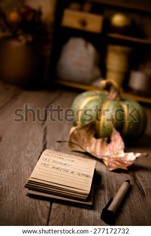 Open notebook with handwritten resolutions on wooden table on the wintage kitchen with Autumn decorations. Shallow DOF, focus on the page. This image is toned