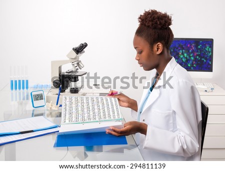 African-american biologist checks records in scientific lab or research facility. Focus on the eyelashes.
