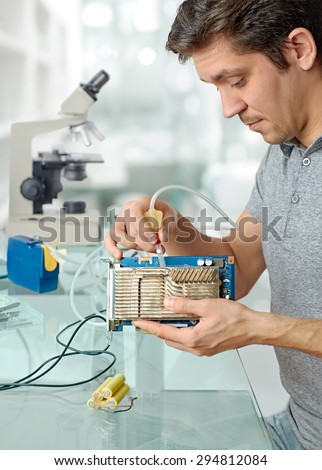 Young male tech cleans faulty computer processor in hardware repair workshop