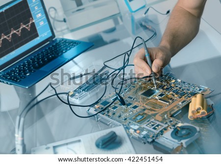 Electronics repair background. Hand of male tech testing motherboard. Shallow DOF, focus on the hand and part of the motherboard. This image is toned.