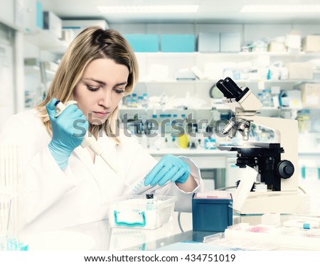 Young female tech or scientist loads liquid sample into test tube with plastic pipette. Shallow DOF, focus on the eyelashes and hand with the tubes. This image is toned.