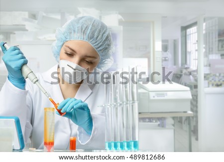 Young female tech or scientist loads liquid sample into test tube with plastic pipette. Shallow DOF, focus on the eyes and hands.