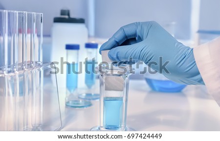Scientific or medical background. Cancer diagnosis: staining of tissue samples. Gloved hands hold a slide glass with tissue samples for histological staining.