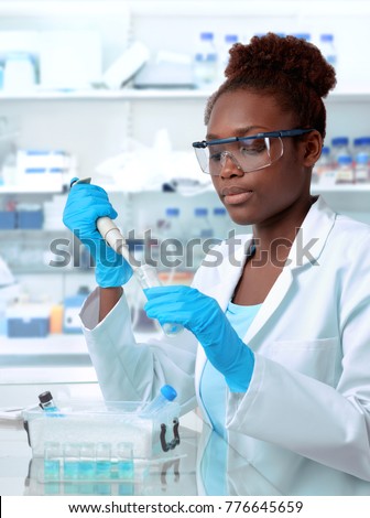 African-american scientist or graduate student in lab coat and protective wear works in modernl laboratory
